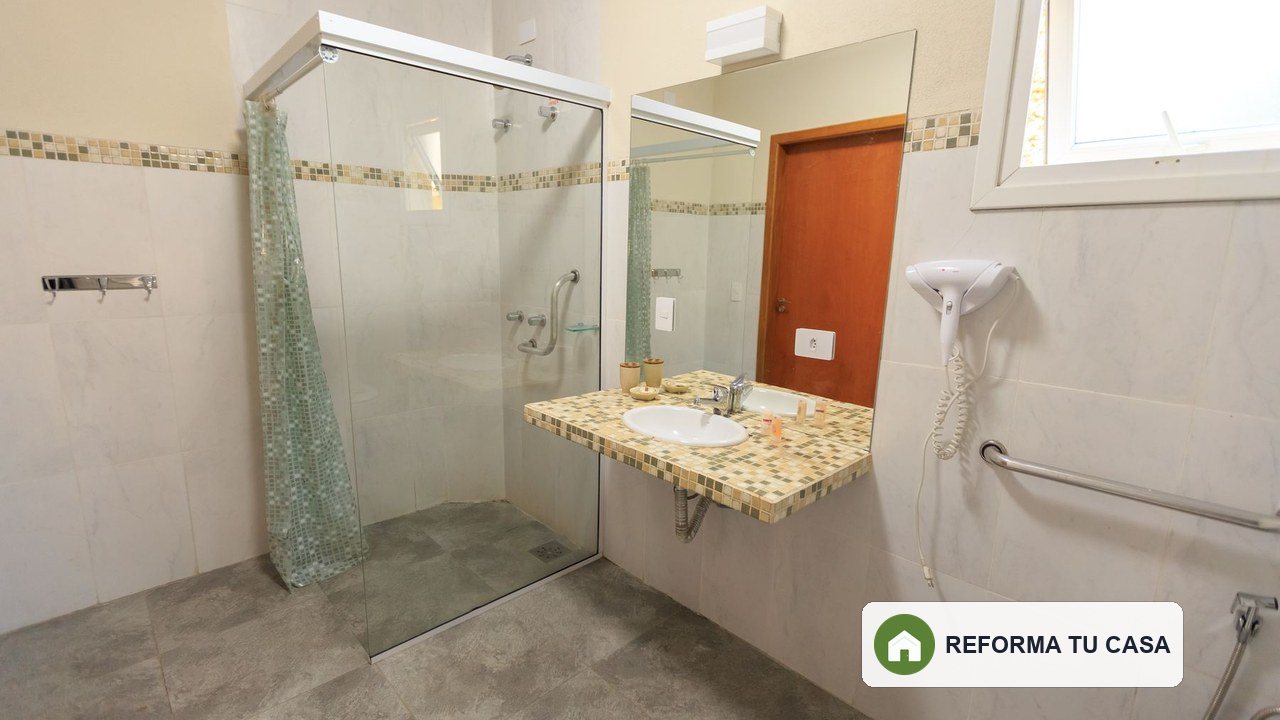 Baño amplio con ducha accesible, barras de apoyo y espacio de maniobra