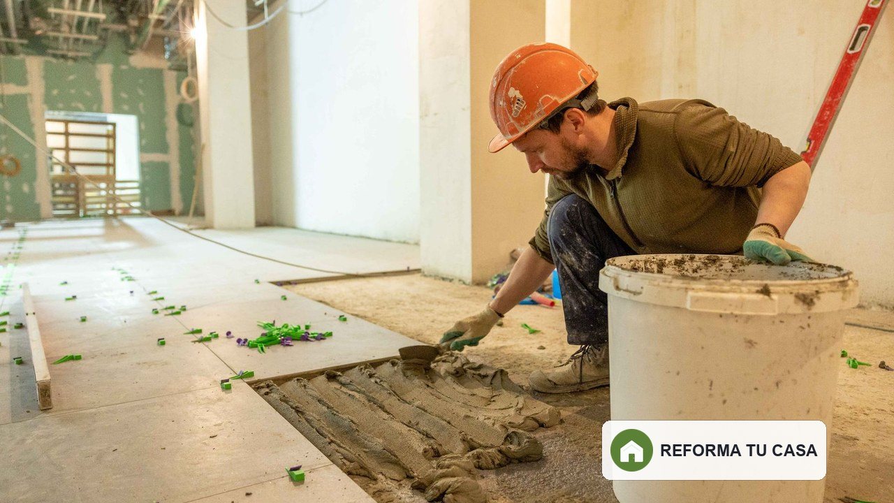 Profesional colocando piezas cerámicas sobre un pavimento interior